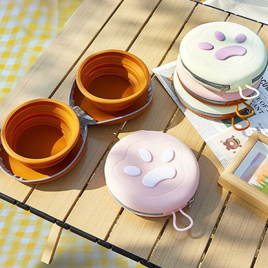 Gamelle pliable pour chien blanche et rose posée sur une table en extérieur, idéale pour les balades.