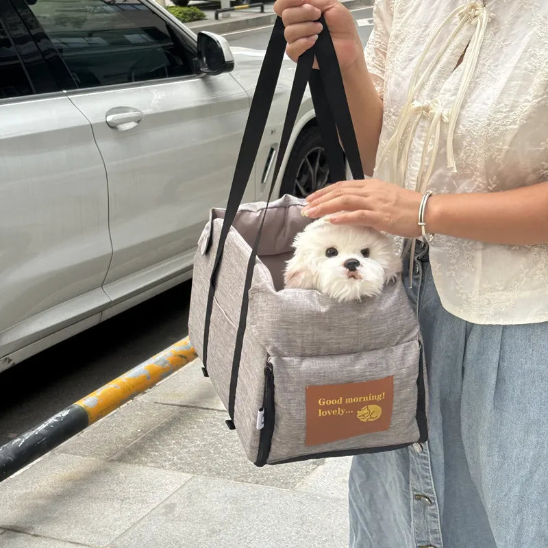 petit chien blanc assis confortablement dans un sac de transport gris pour petit chien
