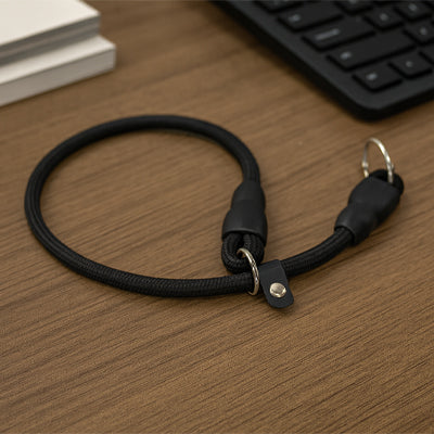 collier ajustable pour chien en nylon noir avec anneau métallique, posé sur une table en bois