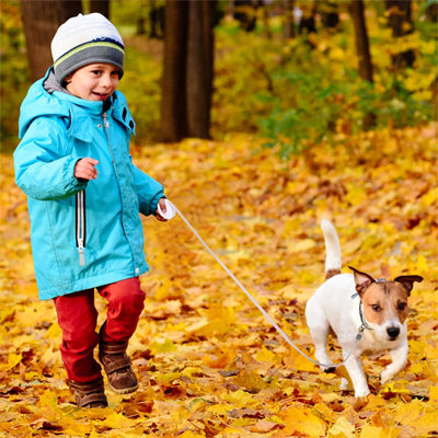 enfant en manteau bleu promenant un chien avec une laisse chiot rétractable
