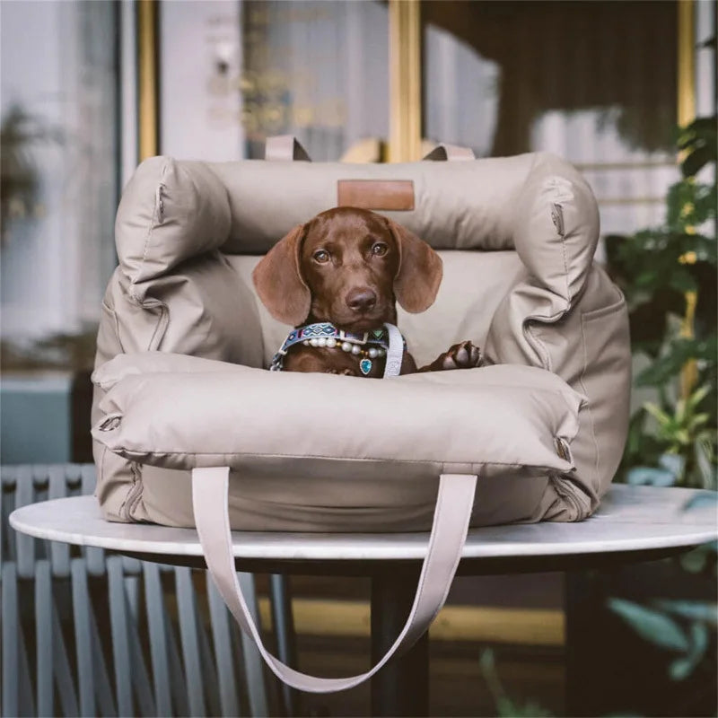 Petit chien couché dans un panier de voiture beige portable, utilisé comme lit d’appoint en voyage.