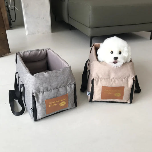 petit chien blanc assis dans un sac de transport gris pour petit chien posé au sol
