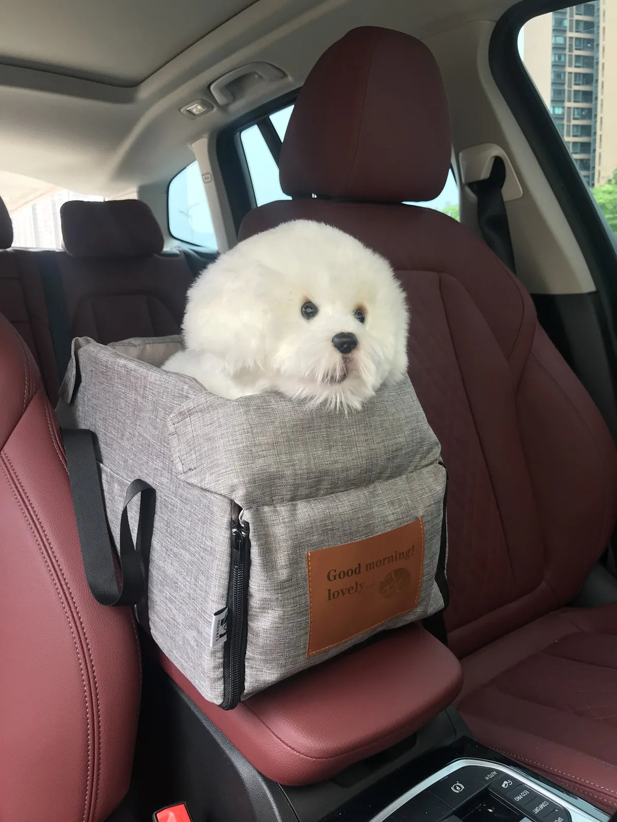 sac de transport gris pour petit chien fixé sur un siège auto avec chiot à l’intérieur