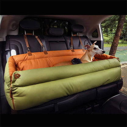 Chien assis dans un siège auto pour chien imperméable vert et orange fixé sur la banquette arrière.