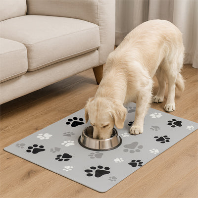 chien blanc mangeant dans sa gamelle posée sur un tapis gamelle pour chien gris décoré de pattes
